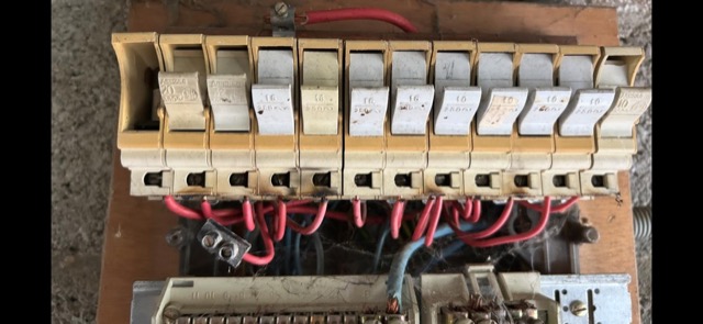Rangée de coupe-circuits à fusibles sur un tableau de génération ancienne.